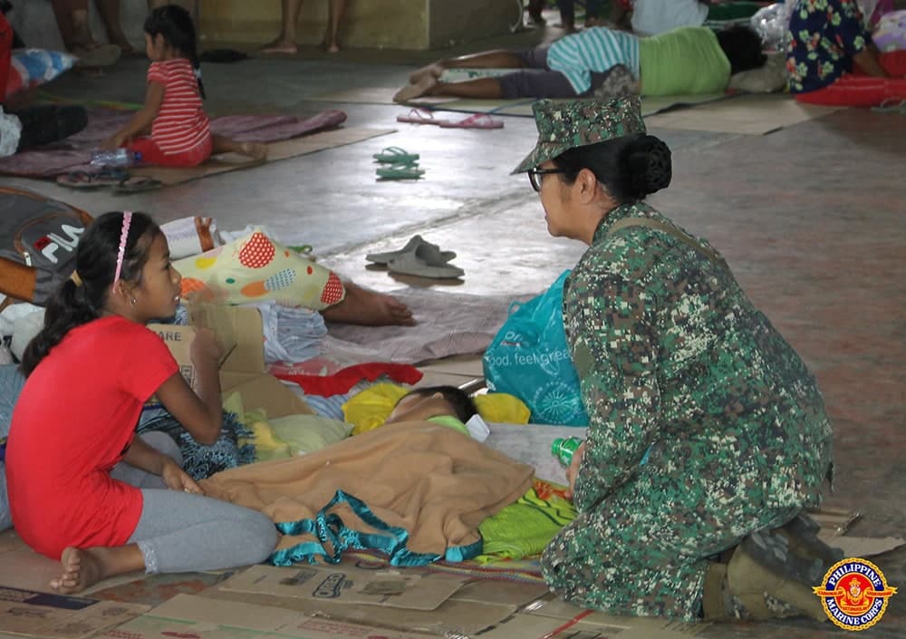 A Marine talking to a civilian during the onslaught of Typhoon Mario